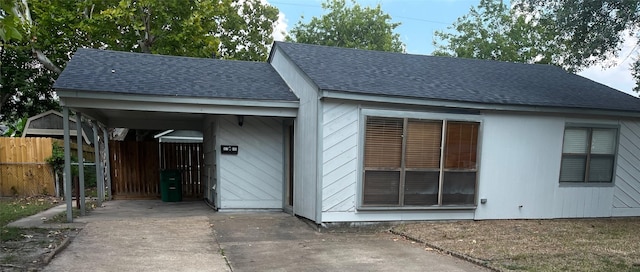 exterior space with a carport, concrete driveway, and fence