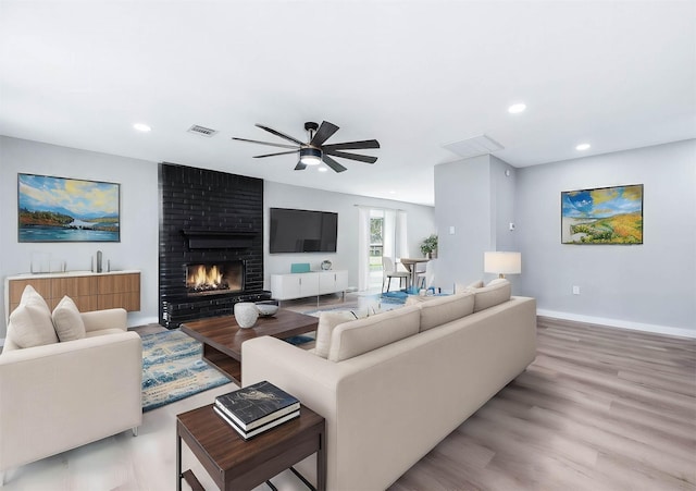 living room featuring recessed lighting, a fireplace, visible vents, baseboards, and light wood-style floors