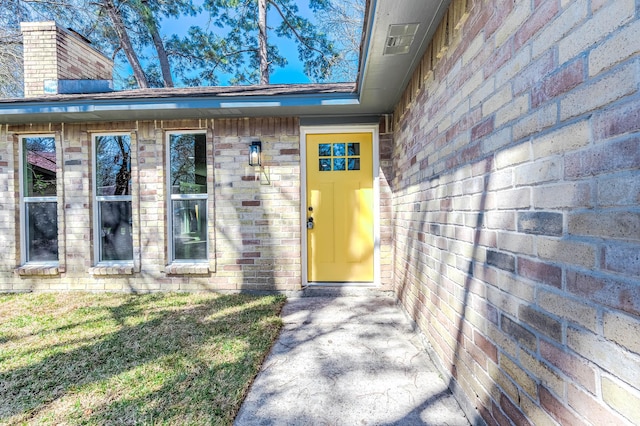 entrance to property featuring brick siding and a chimney