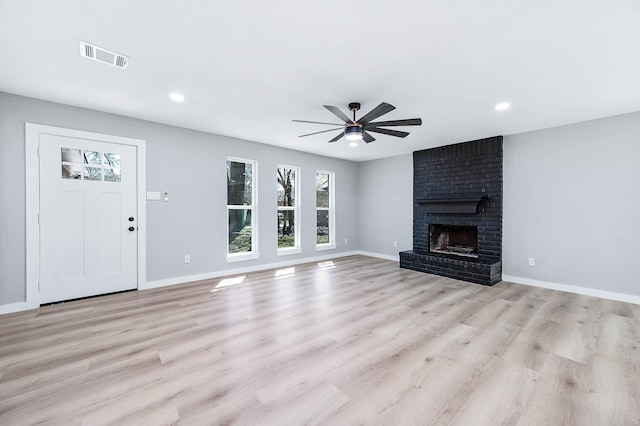 unfurnished living room with baseboards, a brick fireplace, visible vents, and light wood-style floors