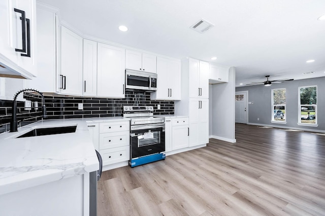 kitchen with visible vents, decorative backsplash, stainless steel appliances, light wood-type flooring, and a sink