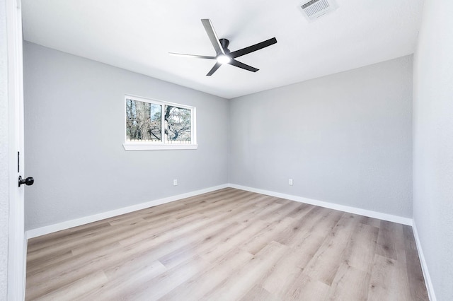 empty room featuring a ceiling fan, visible vents, baseboards, and wood finished floors