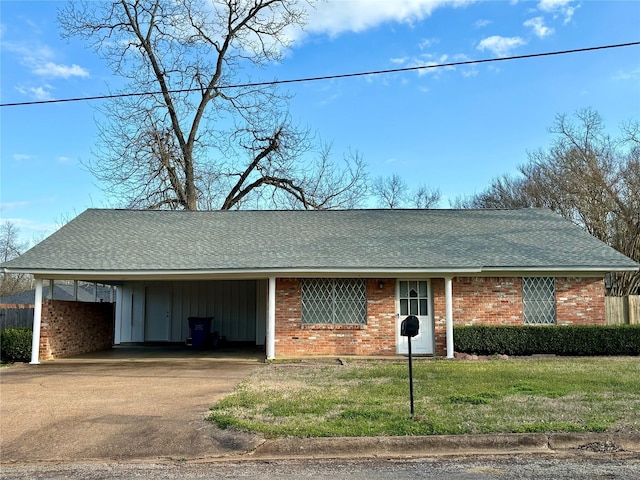 single story home with driveway, an attached carport, roof with shingles, a front lawn, and brick siding