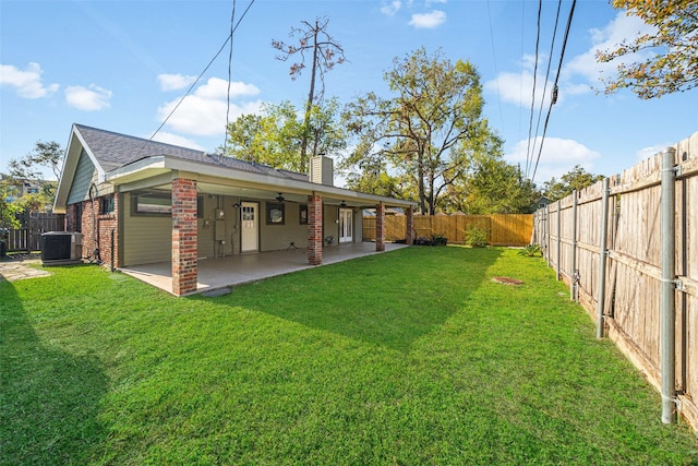 back of property featuring a patio, a fenced backyard, a chimney, a yard, and brick siding