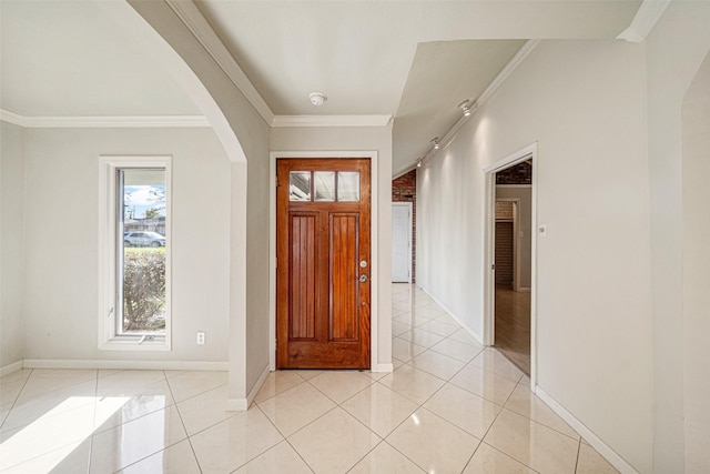 entrance foyer with arched walkways, crown molding, and light tile patterned floors