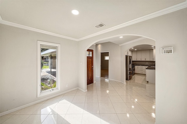 empty room featuring light tile patterned floors, baseboards, visible vents, and arched walkways