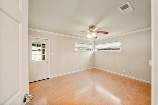 empty room with visible vents, crown molding, light wood-style flooring, and baseboards