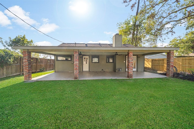 rear view of house featuring a patio area, a fenced backyard, a lawn, and a chimney