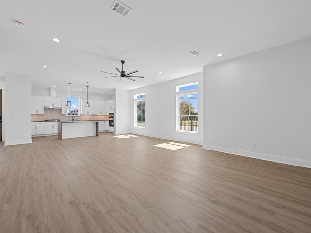 unfurnished living room featuring a ceiling fan, recessed lighting, visible vents, and light wood finished floors