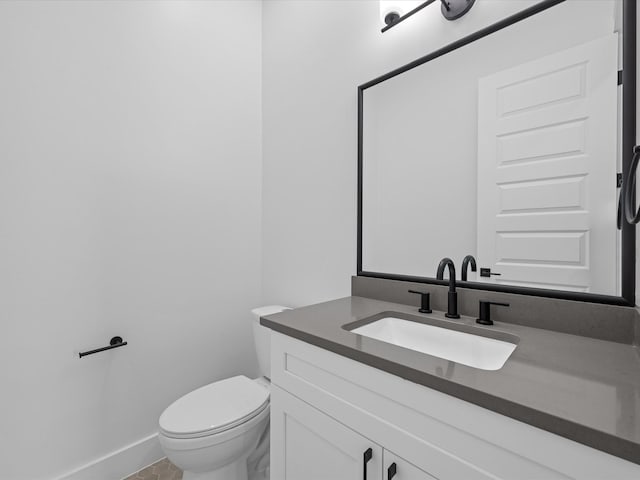 half bathroom featuring vanity, toilet, and baseboards