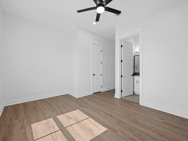 unfurnished bedroom featuring baseboards, ensuite bath, ceiling fan, wood finished floors, and recessed lighting