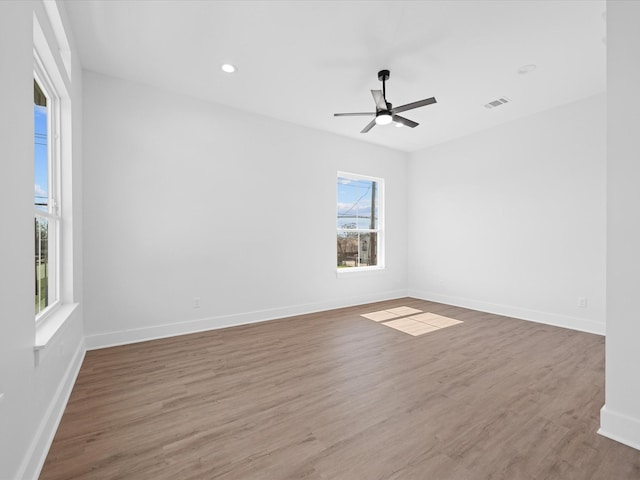 empty room featuring recessed lighting, visible vents, a ceiling fan, wood finished floors, and baseboards