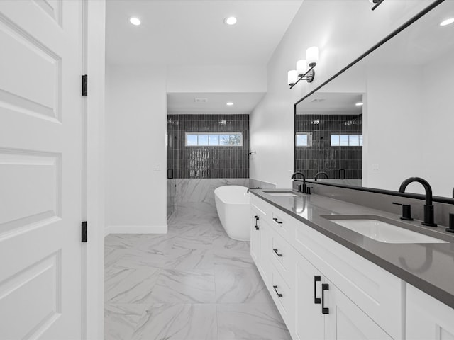 bathroom featuring marble finish floor, a soaking tub, a sink, and recessed lighting