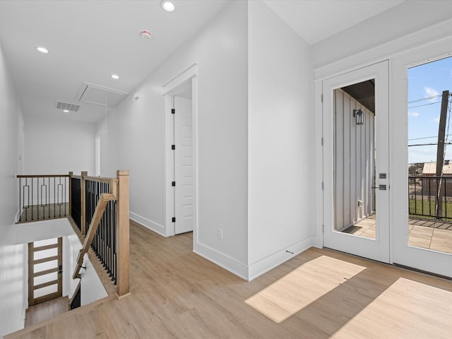 corridor featuring attic access, french doors, wood finished floors, and an upstairs landing