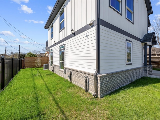 view of side of home with a yard, brick siding, board and batten siding, and a fenced backyard