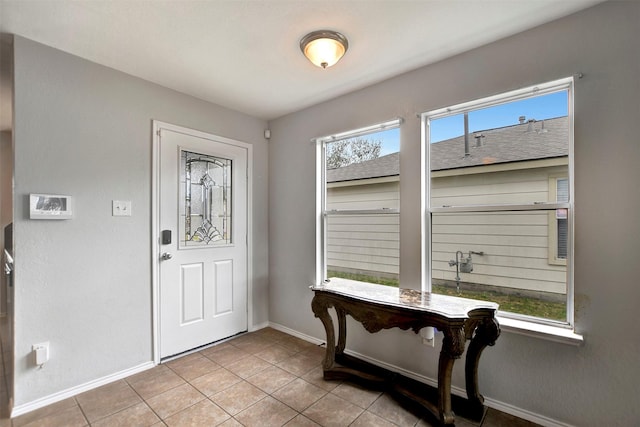 foyer entrance with light tile patterned floors and baseboards