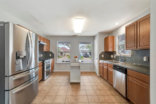 kitchen featuring decorative backsplash, appliances with stainless steel finishes, under cabinet range hood, a sink, and light tile patterned flooring