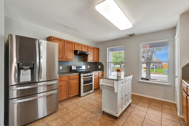 kitchen with light tile patterned floors, visible vents, appliances with stainless steel finishes, brown cabinetry, and under cabinet range hood