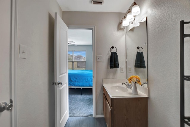 ensuite bathroom with visible vents, a textured wall, wood finished floors, ensuite bathroom, and vanity