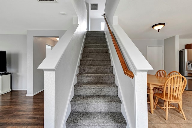 stairs featuring baseboards, visible vents, and tile patterned floors