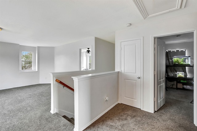 corridor featuring baseboards, dark carpet, and an upstairs landing