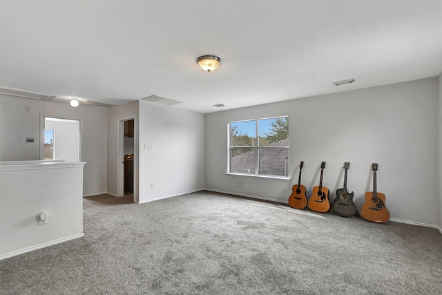 unfurnished room featuring carpet, attic access, visible vents, and baseboards