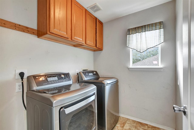 clothes washing area featuring visible vents, cabinet space, washer and clothes dryer, and baseboards