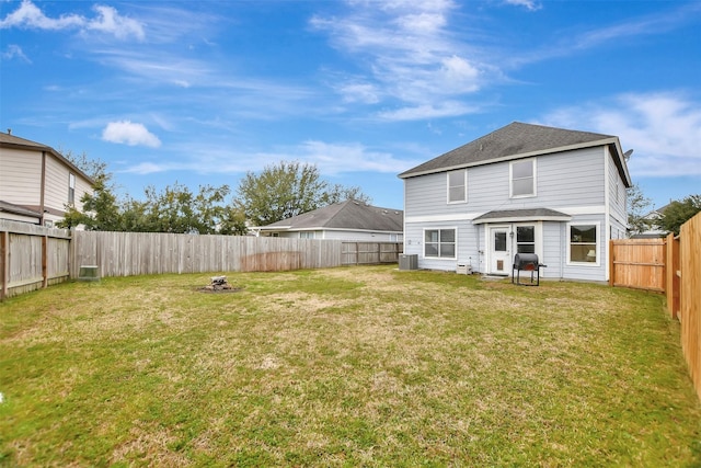 rear view of house with an outdoor fire pit, a fenced backyard, a lawn, and central AC unit