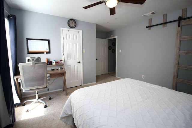 bedroom with a barn door, visible vents, baseboards, ceiling fan, and carpet
