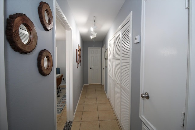hall with rail lighting, baseboards, and light tile patterned floors