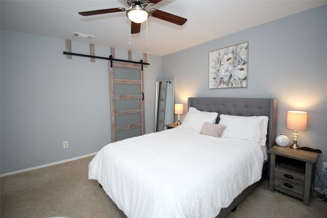 carpeted bedroom with a ceiling fan, visible vents, baseboards, and a barn door