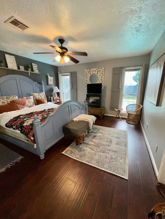 bedroom featuring baseboards, visible vents, dark wood finished floors, ceiling fan, and a textured ceiling