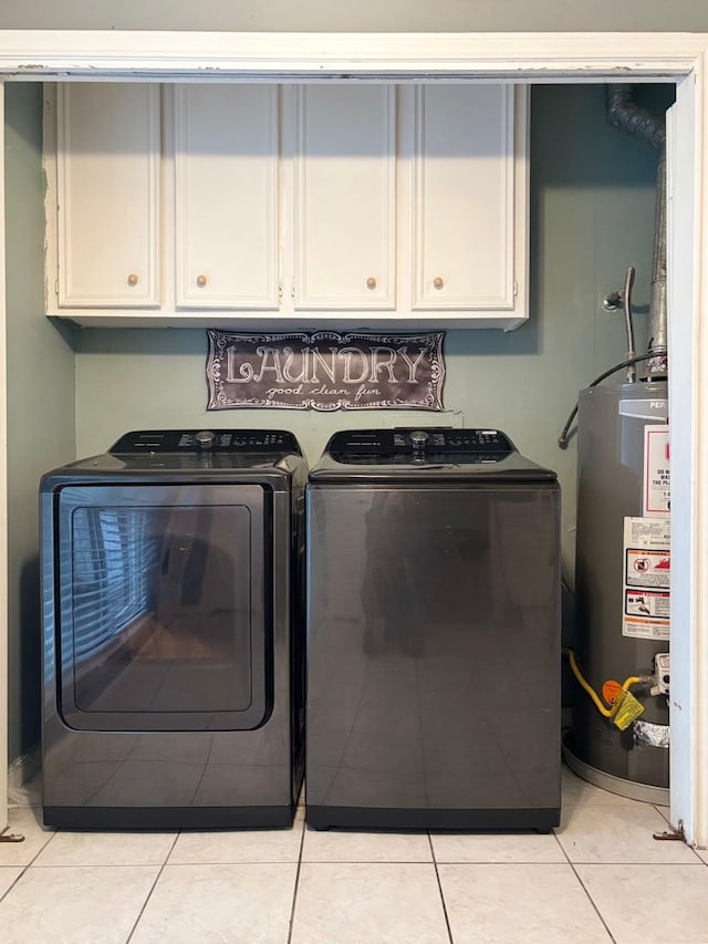 washroom with water heater, washing machine and dryer, cabinet space, and light tile patterned flooring