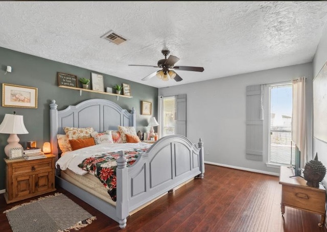 bedroom with visible vents, dark wood-type flooring, baseboards, a textured ceiling, and a ceiling fan