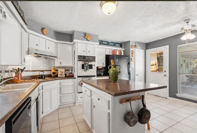 kitchen with dark countertops, black appliances, light tile patterned flooring, white cabinetry, and a sink