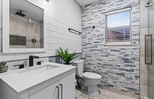 full bathroom featuring tile walls, toilet, vanity, a shower stall, and tile patterned floors