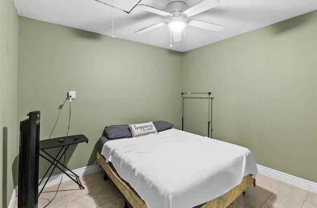 bedroom with a ceiling fan, attic access, light tile patterned flooring, and baseboards