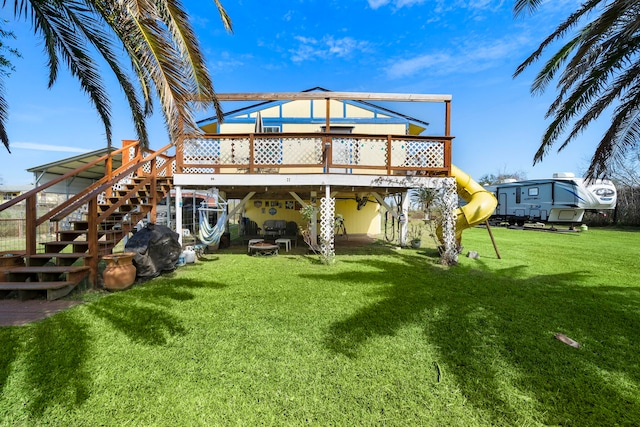 rear view of property with a yard, stairway, and a wooden deck