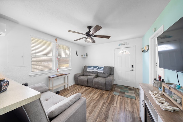 living area featuring a ceiling fan, a textured ceiling, and wood finished floors