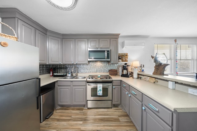 kitchen featuring appliances with stainless steel finishes, a sink, and gray cabinetry