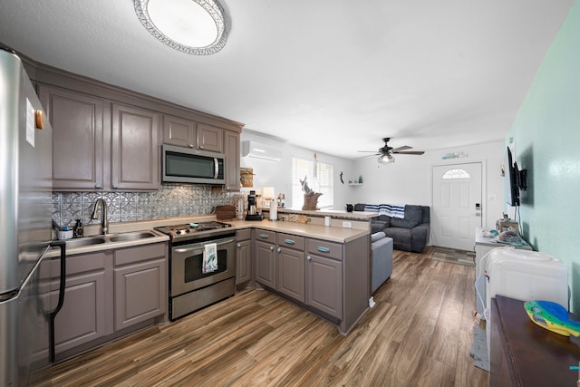 kitchen with a wall unit AC, gray cabinetry, stainless steel appliances, a peninsula, and open floor plan