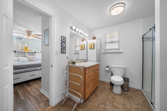 ensuite bathroom featuring a stall shower, baseboards, toilet, ensuite bath, and vanity