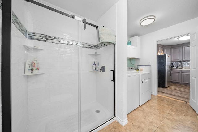 full bath with washer and dryer, tile patterned flooring, a shower stall, and decorative backsplash