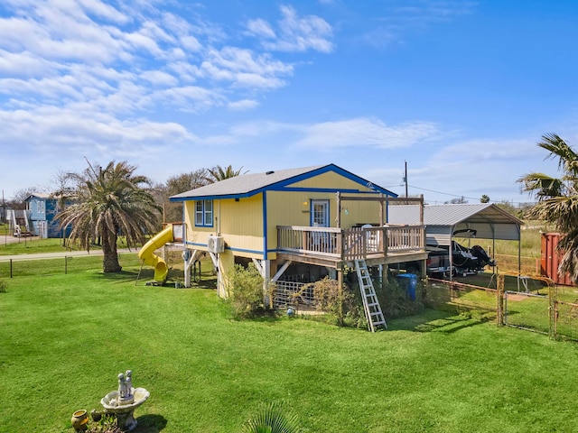 rear view of house featuring a deck, a carport, and a yard