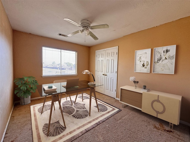 carpeted office space with ceiling fan, visible vents, and baseboards