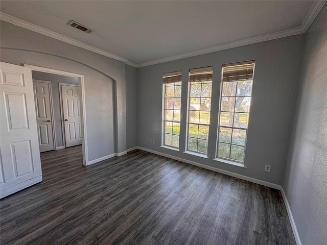 empty room with dark wood-style floors, baseboards, visible vents, and crown molding