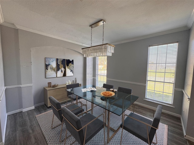 dining space featuring a textured ceiling, ornamental molding, wood finished floors, and baseboards