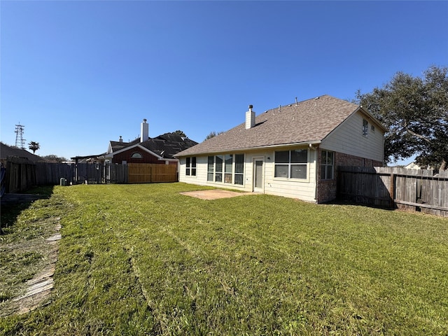 rear view of house featuring a fenced backyard, a chimney, a lawn, and roof with shingles