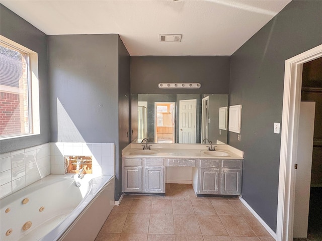 bathroom with double vanity, a sink, a jetted tub, and tile patterned floors