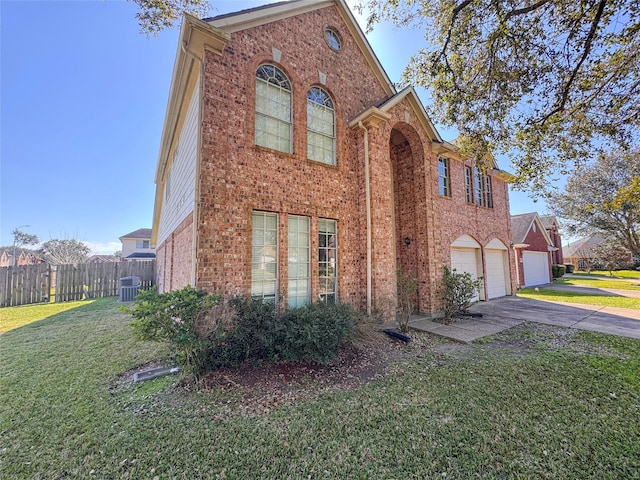 traditional-style house featuring brick siding, an attached garage, fence, driveway, and a front lawn